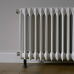 A radiator against a clear wall and a wood floor